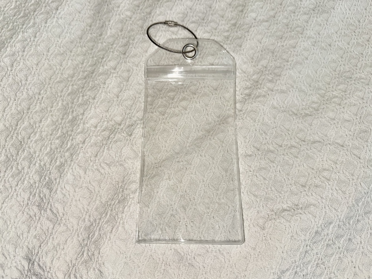 Image of a clear cruise luggage tag set, featuring durable plastic tags designed to protect and display cruise line boarding passes. The set includes several transparent tags with metal loop fasteners, ensuring secure attachment to luggage. Each tag is sized to fit standard cruise documents and includes a waterproof seal to keep the contents safe from moisture. The tags are displayed neatly against a plain background, highlighting their practicality and sturdiness for cruise travelers.