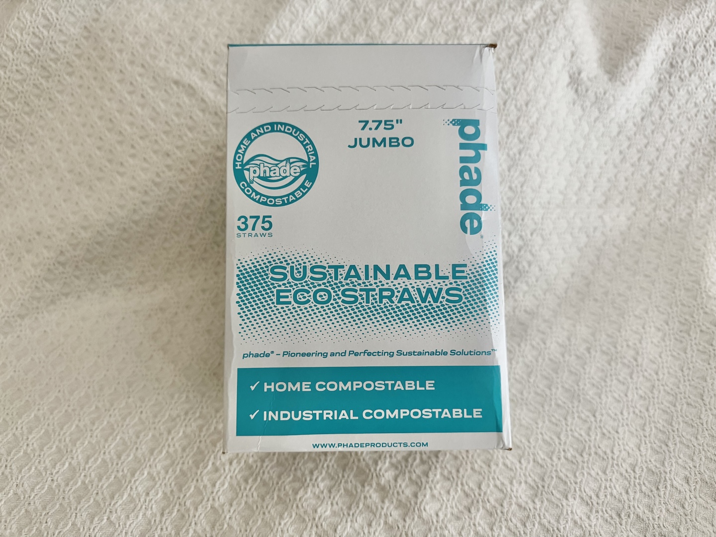 Image of a box of sustainable eco straws, made from biodegradable and eco-friendly materials. The box is decorated with earthy tones and green accents, emphasizing its environmentally conscious design. Several straws are displayed next to the box, showcasing their natural appearance and sturdy construction, suitable for various beverages. The packaging includes information about the straws being compostable, reusable, or made from materials like bamboo or paper, highlighting their role in reducing plastic waste.