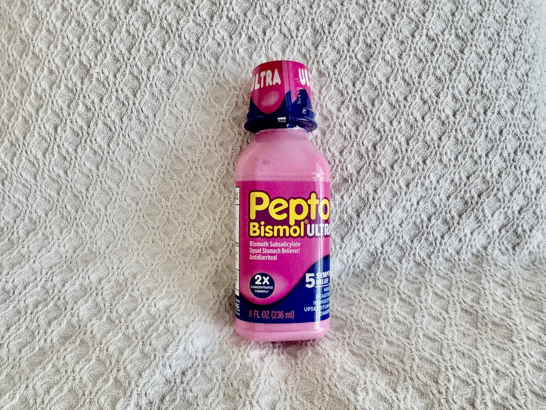 Image of a bottle of Pepto Bismol Ultra, a pink-colored over-the-counter liquid medication for digestive relief. The bottle features a bright pink label with the Pepto Bismol logo and 'Ultra' prominently displayed, indicating its stronger formula. The label also highlights the product's use for relieving symptoms like heartburn, indigestion, nausea, upset stomach, and diarrhea. The bottle has a child-resistant cap and is shown standing upright against a plain background, with the product details clearly visible.